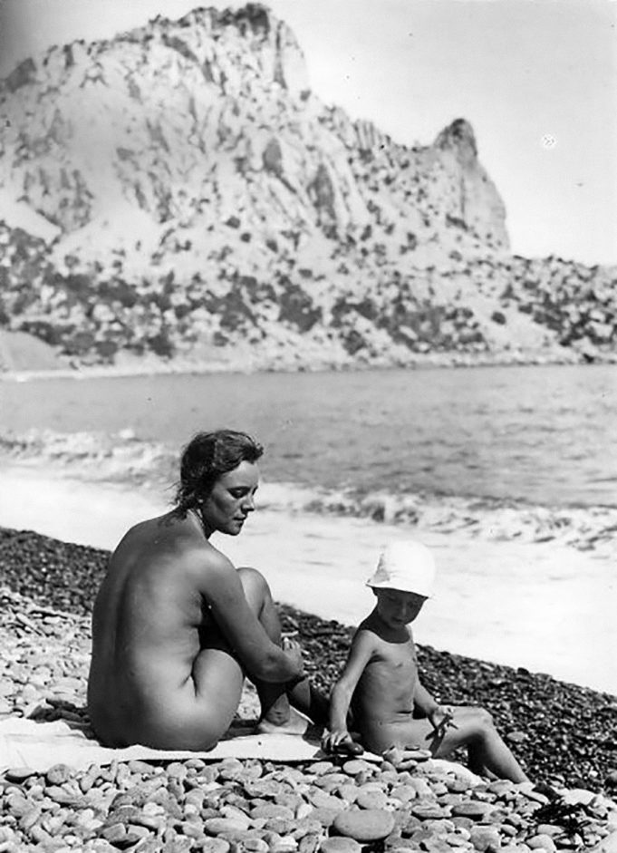 Две голые девушки фотографируются на пляже.